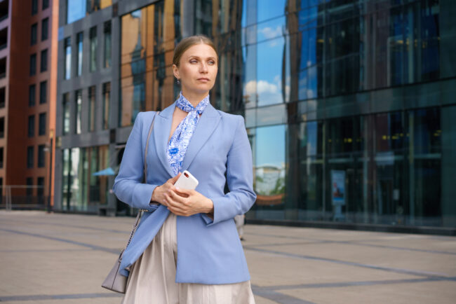 Entrepreneur with confident mindset standing outside corporate buildings after making mental shift from employee thinking
